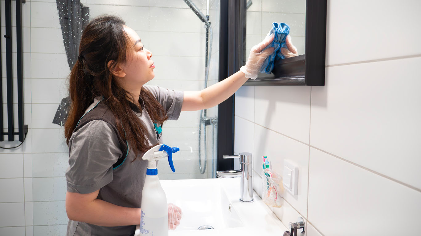 Montico anställd tvättar spegel i badrum.